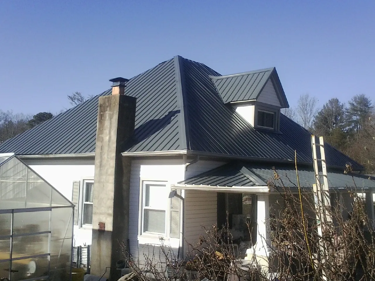 Dark blue standing seam metal roof on a white farmhouse with dormer — Slate & Tile Roof Repair by Roofing Brothers in Brookville