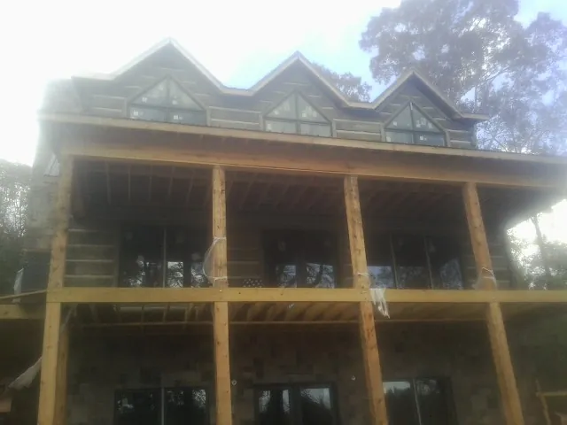 Dormers and porch framing on a large log home under construction — Roof Coating work by our crew in Brookville