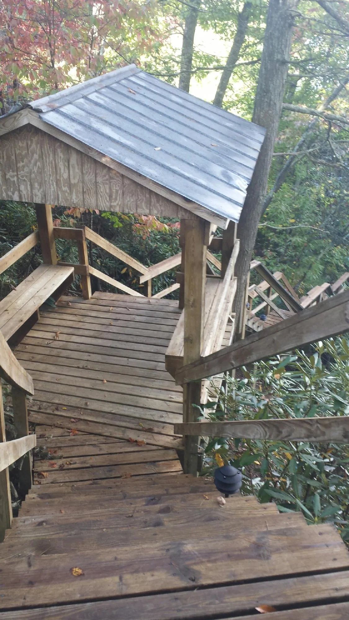 Metal roofed shelter over wooden steps on a wooded walkway — Skylight Repair & Installation work by our crew in Brookville
