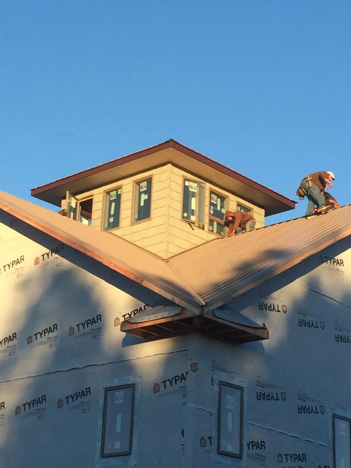 Roofers working around a rooftop cupola on a new metal roof at sunset — Roof Waterproofing in Brookville by Roofing Brothers